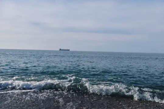 Одинокий грузовой корабль на горизонте спокойного моря