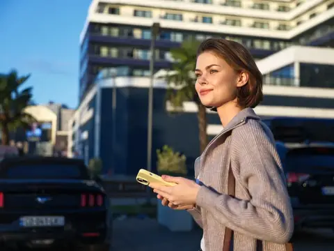 Молодая женщина с телефоном на фоне городских зданий
