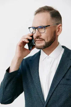 Мужчина в очках и пиджаке говорит по телефону