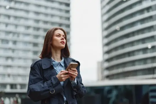 Молодая женщина с телефоном на фоне высотных зданий