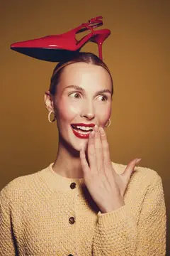 Удивленная женщина с красной туфлей на голове