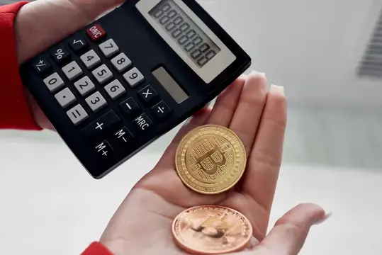 Руки держат калькулятор и золотые монеты биткоин