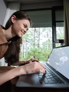 Молодая женщина с радостным выражением лица работает за ноутбуком в тёплой, уютной обстановке