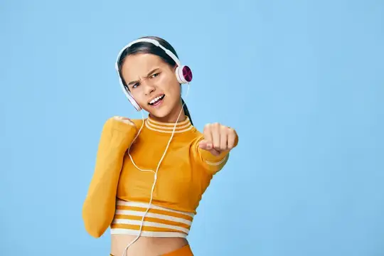 Яркая спортивная сцена: сосредоточенная женщина-атлет в топе, гарнитуре и напульсниках выполняет динамичное упражнение на ярко-голубом фоне