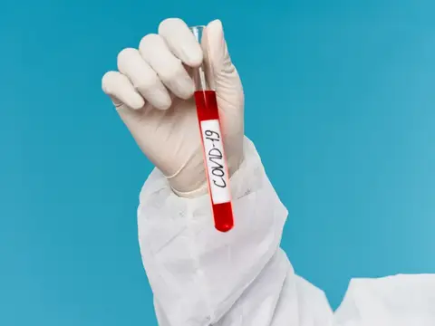 Рука в белой перчатке держит пробирку с анализом на COVID-19