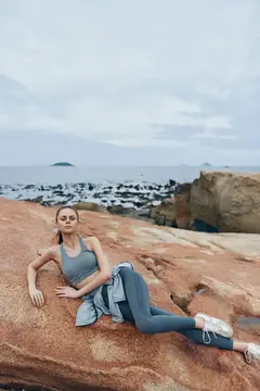 Спортивная девушка лежит на скалах у моря в пасмурный день