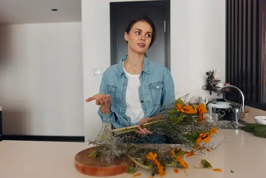 Молодая женщина в джинсовой куртке собирает букет из желтых цветов на кухне