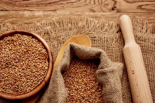 Пшеничные зёрна в мешковине и деревянной миске на столе