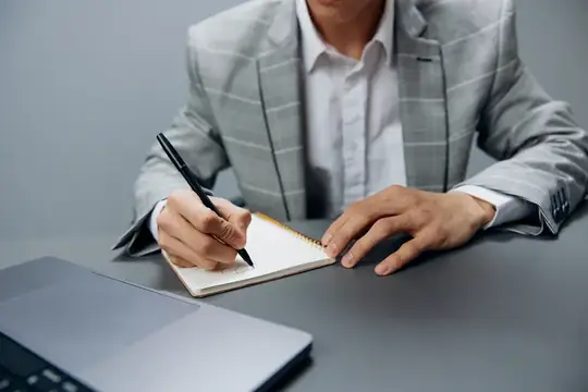 Менеджер в сером костюме сидит перед ноутбуком, офисный руководитель