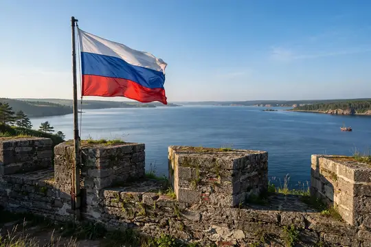 Российский флаг развевается над старинной крепостью у широкой реки