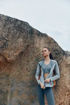 Спортивная девушка стоит на фоне большой скалы