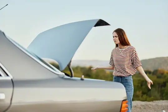 Расстроенная девушка смотрит на открытый багажник автомобиля