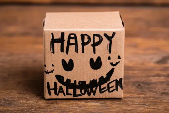 Картонная коробка с нарисованной улыбкой и надписью Happy Halloween