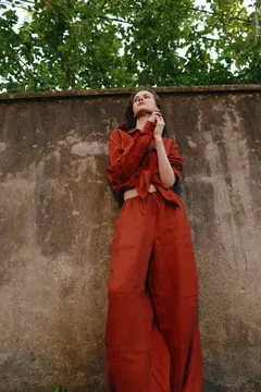 Молодая женщина в терракотовом костюме у старой стены