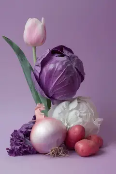 Потрясающая композиция из фиолетовых тюльпанов, капусты и красного картофеля, создающая яркий натюрморт