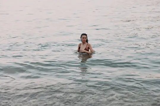Молодая женщина по грудь в воде спокойного моря