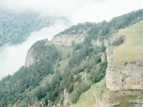 Горный пейзаж с отвесными скалами и облаками в ущелье
