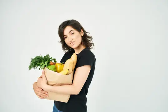 Милый брюнетка с сумкой продуктов в руках, покупки в супермаркете