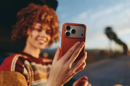 Рыжеволосая девушка смотрит в смартфон на закате