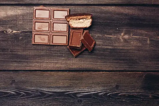 Плитка шоколада и кусочки с начинкой на тёмных деревянных досках