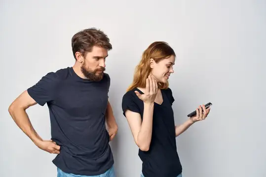 Весёлая молодая пара с телефоном в руках, эмоции, студийный образ жизни