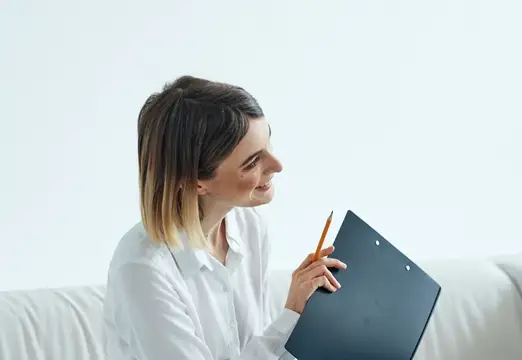 Улыбающаяся женщина с планшетом и карандашом на светлом фоне