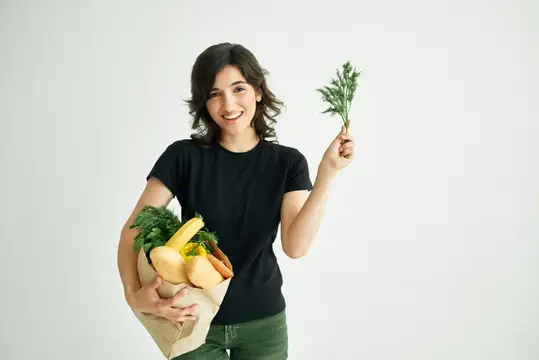 Веселая женщина в черной футболке с пакетом продуктов здорового питания