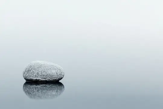 Одинокий серый камень с отражением на гладкой воде