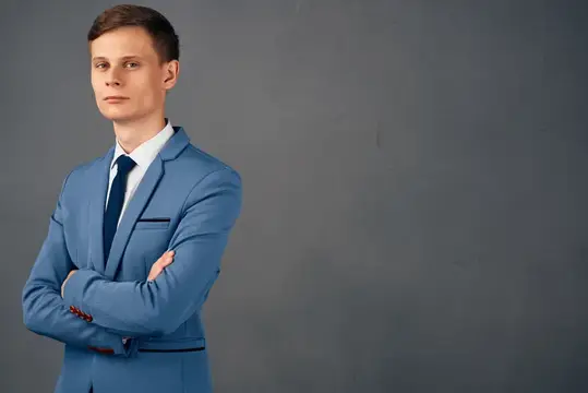Уверенный молодой мужчина в синем костюме на сером фоне