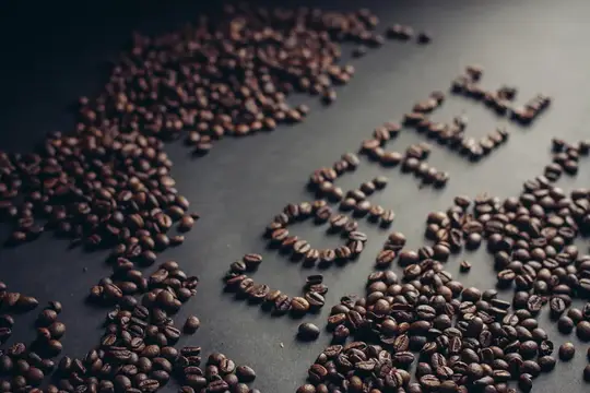 Кофейные зёрна, выложенные словом coffee на тёмном столе