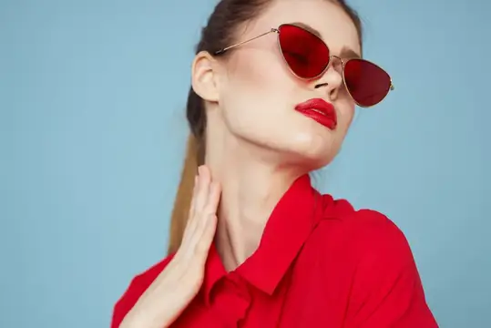 Светловолосая женщина в красных солнцезащитных очках на голубом фоне