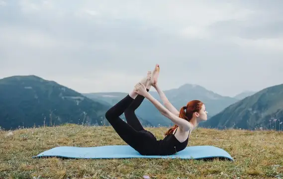 Спортивная женщина на природе занимается йогой на фоне гор