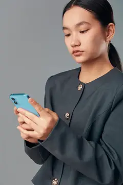 Молодая женщина с серьёзным выражением лица смотрит на смартфон в студии
