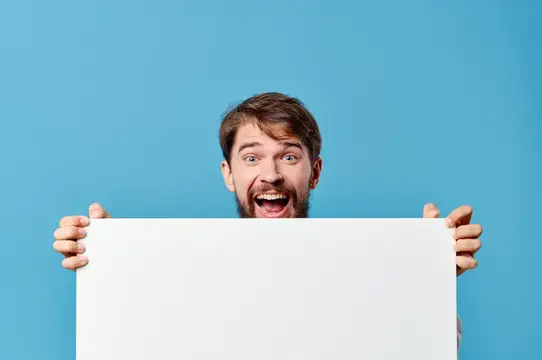 Удивлённый бородатый мужчина выглядывает из-за белого листа