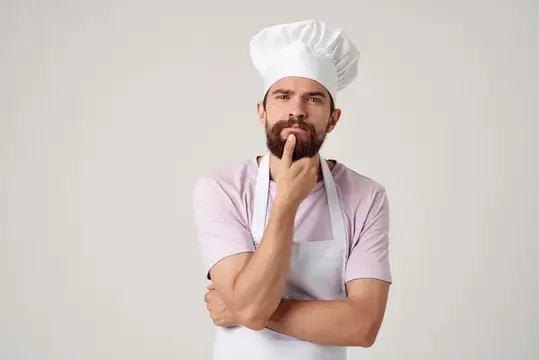 Эмоциональный мужчина-шеф-повар работает на кухне ресторана, обслуживая гостей