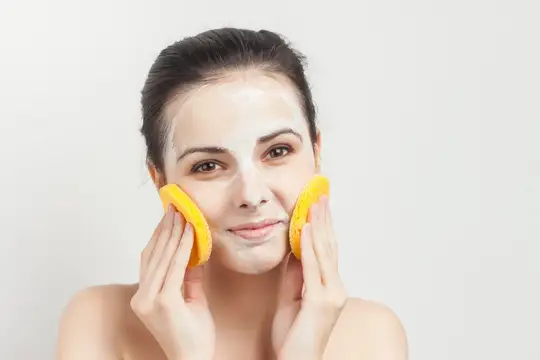 Молодая женщина с косметической маской наносит средство спонжами
