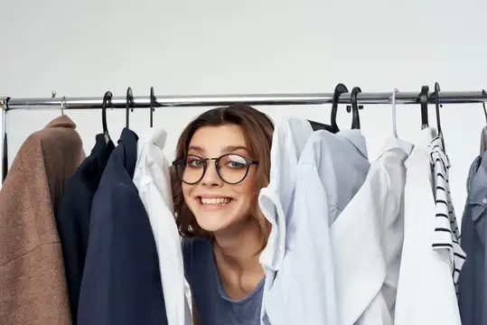 Женщина в очках в магазине одежды, покупательница, распродажа, светлый фон