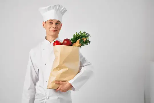 Мужчина в униформе шеф-повара занимается упаковкой продуктов для службы доставки еды, готовит здоровую пищу