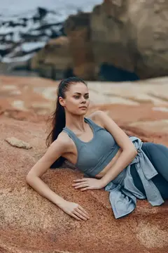 Молодая женщина в спортивной одежде лежит на скалах