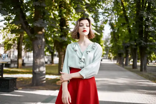 Привлекательная женщина в красной юбке гуляет по парку, наслаждаясь свежим воздухом и активным образом жизни