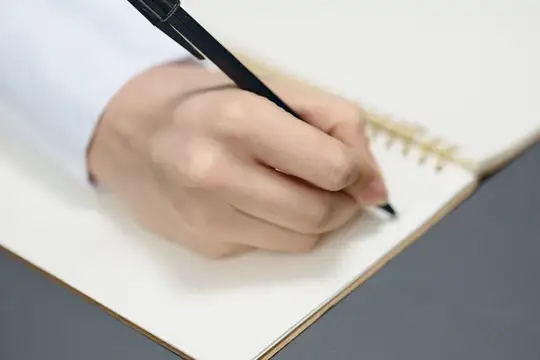 Крупный план руки молодой студентки, фрилансерки или журналистки, которая пишет статью, используя тетрадь в сером современном домашнем офисе