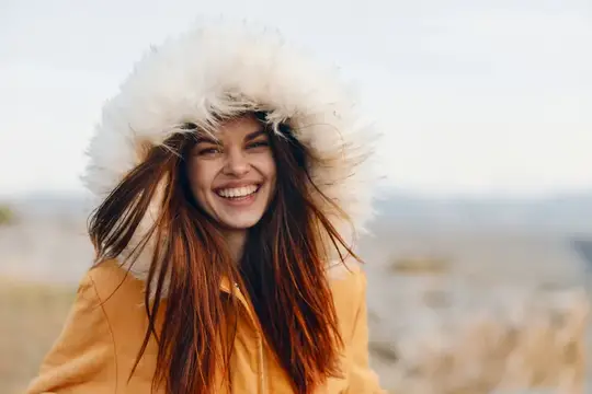 Улыбающаяся женщина в оранжевом пальто с меховым капюшоном
