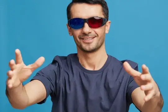 Улыбающийся мужчина в красно-синих 3D-очках тянет руки к камере