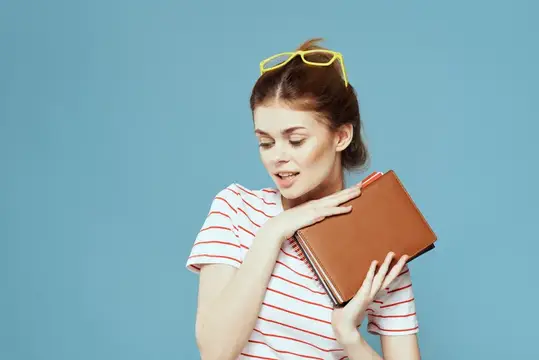 Молодая женщина с книгой и желтыми очками на голове на синем фоне