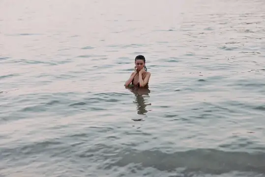 Молодая женщина по грудь в воде спокойного моря