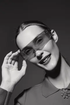 Молодая женщина поправляет прозрачные очки на черно-белом портрете