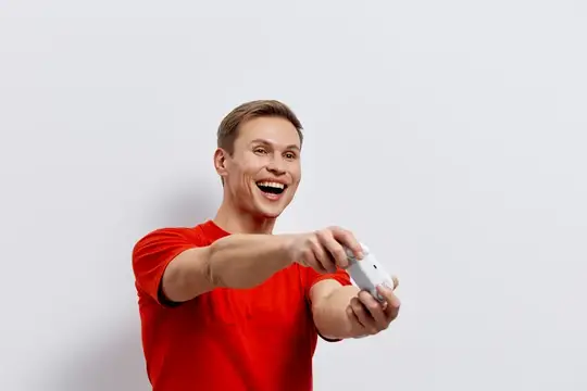 Улыбающийся парень в красной футболке играет в видеоигру