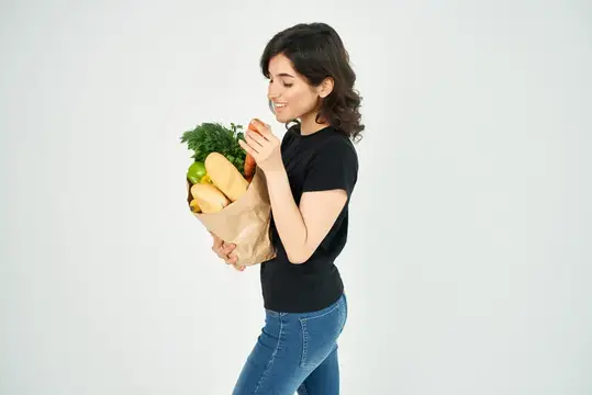 Симпатичная брюнетка в черной футболке с пакетом продуктов из супермаркета