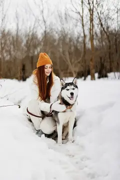 Молодая женщина играет в снегу с собакой