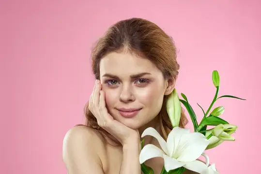Молодая женщина с белыми лилиями на розовом фоне